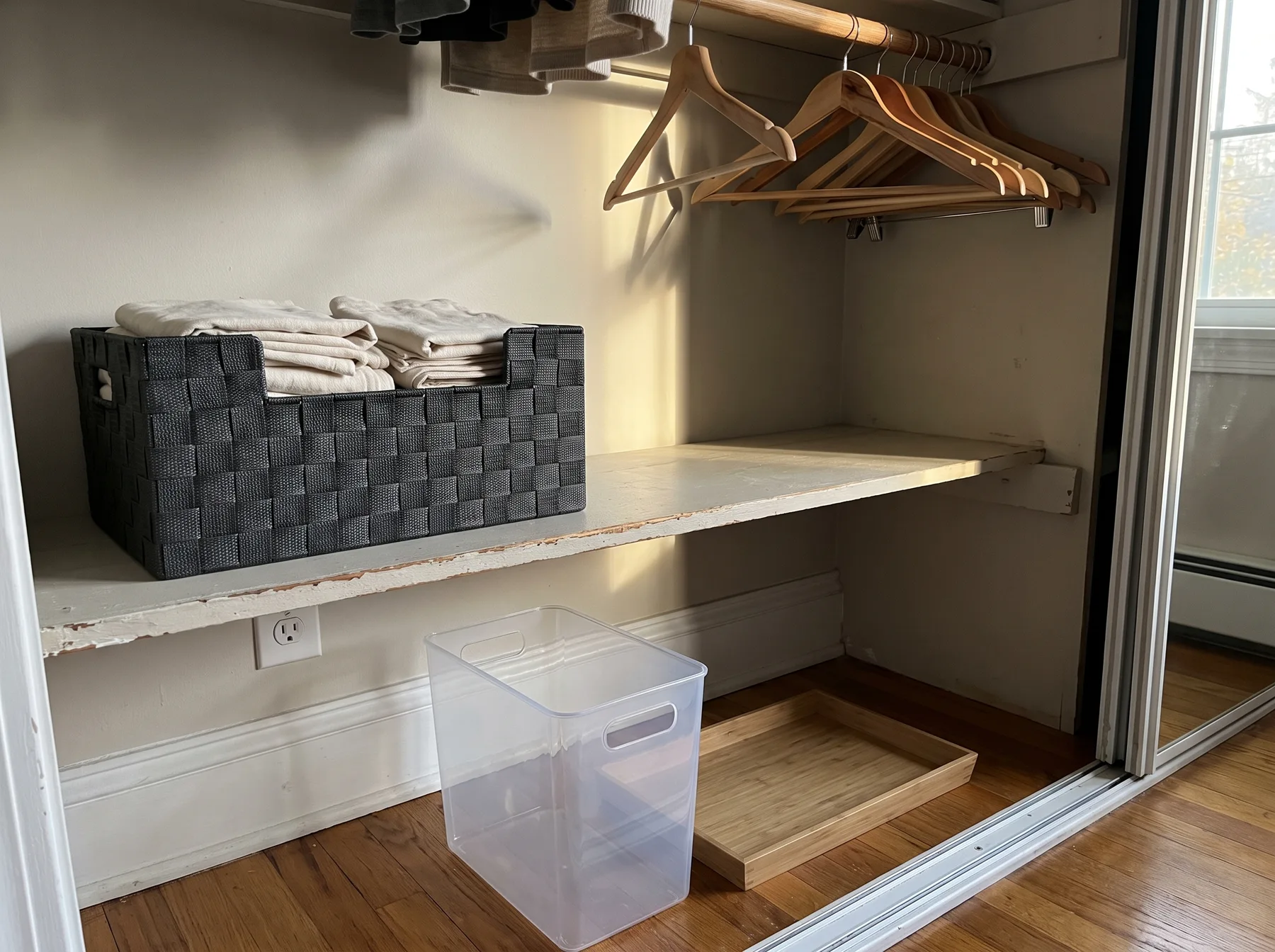 Closet holds folded linens in a shelf bin beside empty organizers and wooden hangers.