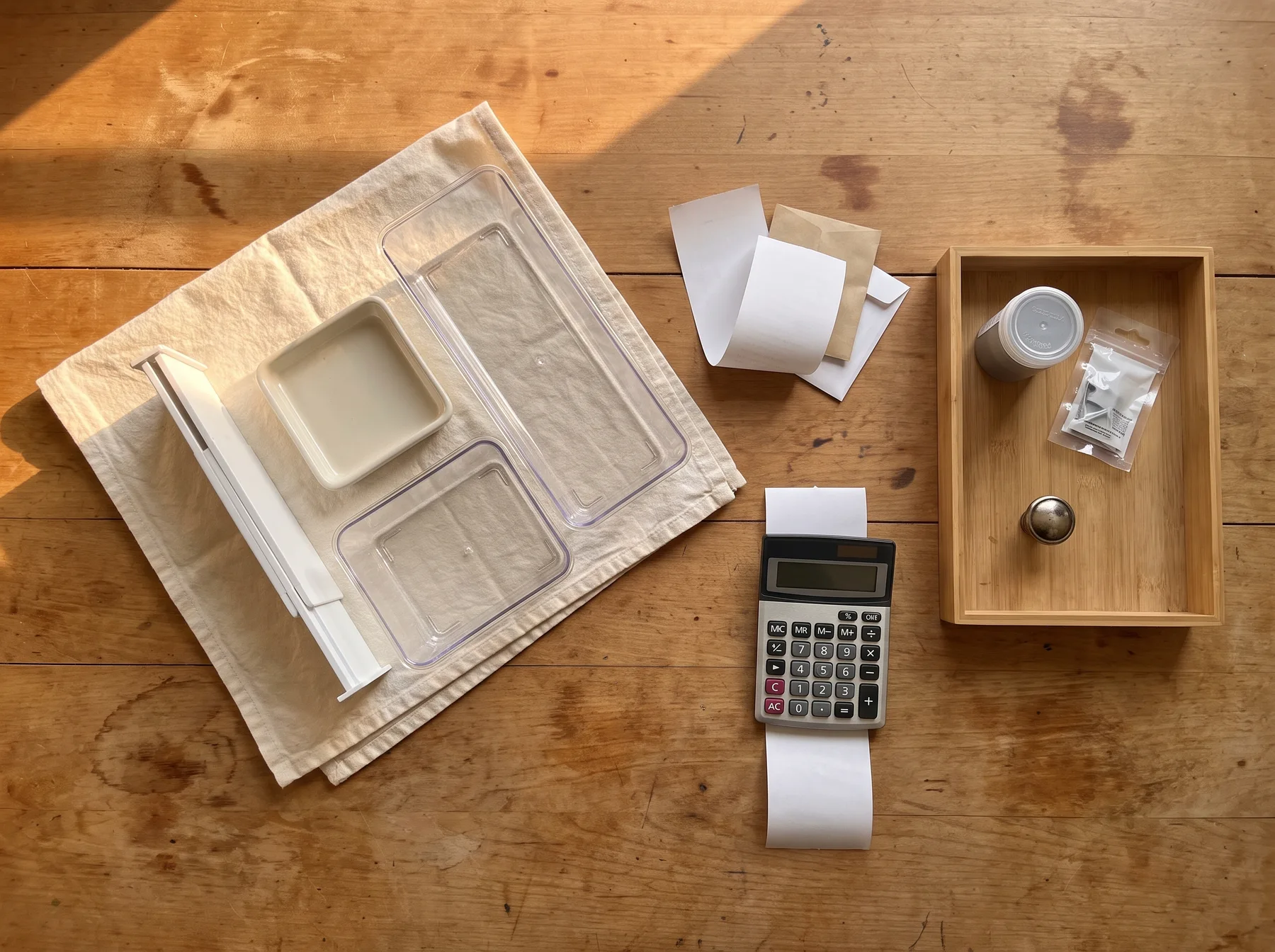 Calculator, removable organizers, receipts, and hardware are arranged on a wooden table for budgeting.